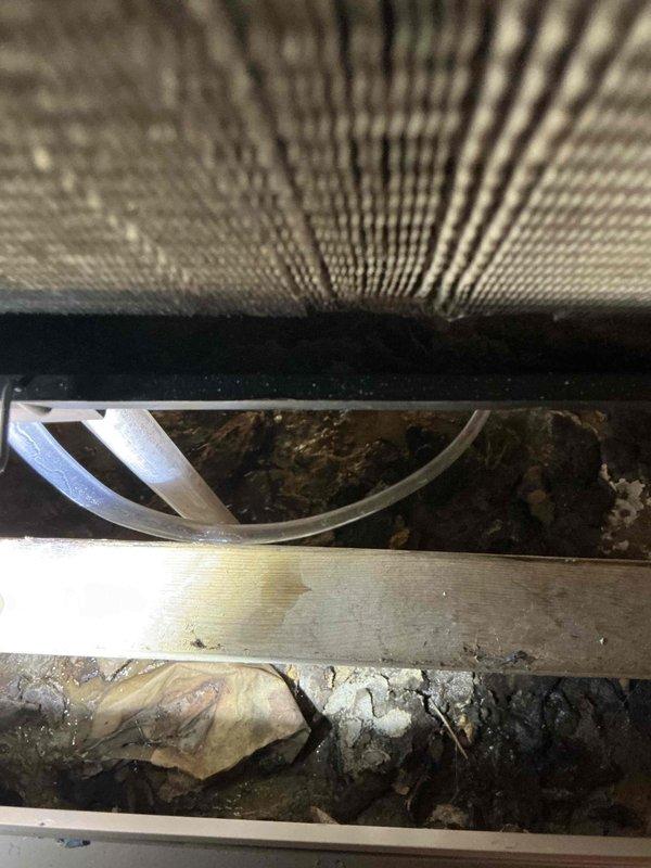 Responded to service call for air conditioning unit not operating properly in garage area. Upon inspection, found heavily soiled air intake filter restricting airflow and missing condensate drain line causing water to pool beneath the approximately 2-year-old unit. Customer had attempted to clean intake prior to arrival. Inspected interior components and confirmed accumulation of dust and debris throughout the system. Addressed drainage issue and verified proper airflow restoration to return unit to normal operation.
