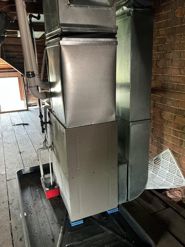 Performed routine maintenance and inspection on residential split HVAC system consisting of attic-mounted air handler with green metal supply ductwork and rooftop condenser unit. Verified proper operation of both indoor and outdoor components, confirmed electrical connections at disconnect box were secure, and ensured adequate airflow through condenser coils and air handler. System operating within normal parameters upon completion of service.