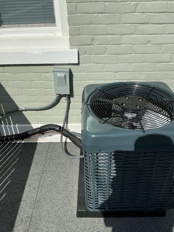 Performed routine maintenance and inspection on residential split HVAC system consisting of attic-mounted air handler with green metal supply ductwork and rooftop condenser unit. Verified proper operation of both indoor and outdoor components, confirmed electrical connections at disconnect box were secure, and ensured adequate airflow through condenser coils and air handler. System operating within normal parameters upon completion of service.