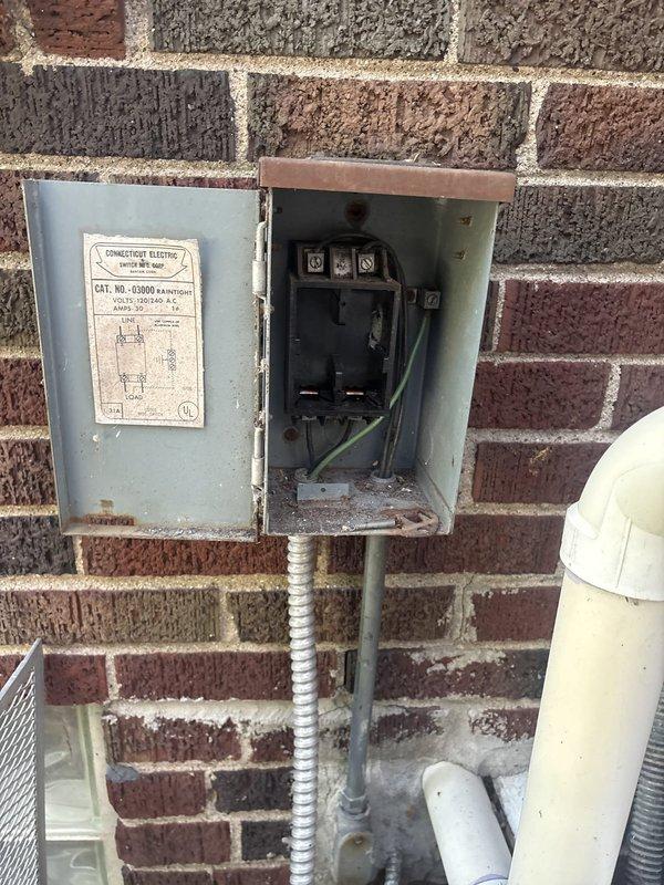 Responded to service call for non-functioning air conditioning system. Upon arrival, tested thermostat operation and confirmed AC unit failed to start. Performed voltage diagnostics at contactor and discovered no output voltage present. Conducted further electrical testing at outdoor disconnect box and identified abnormal voltage reading of only 25 volts on one leg of the power supply, indicating a significant electrical supply issue upstream of the HVAC equipment. Inspected main electrical panel and outdoor disconnect components. Documented findings with photographs of both the outdoor AC disconnect box mounted on exterior wall and the interior electrical breaker panel. Determined that the low voltage condition requires electrical service to diagnose and repair the power supply issue before HVAC system can be restored to operation.