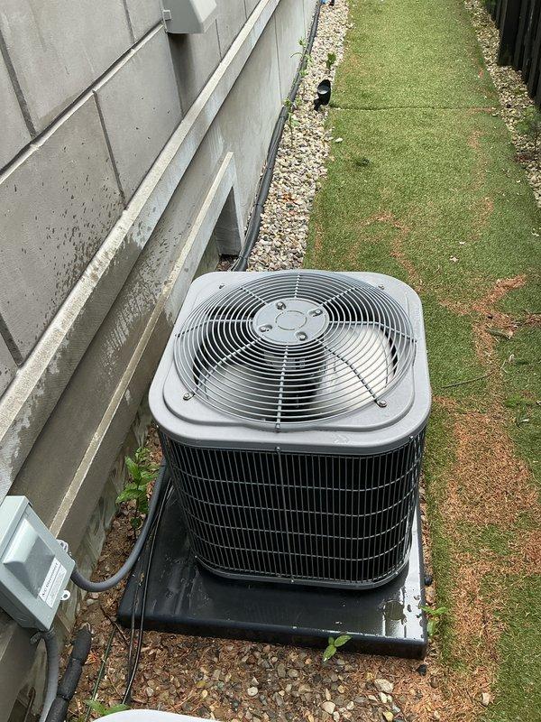 Completed Gold AC Inspection on two 8-year-old outdoor condensing units serving a multi-zone residential system with air handler located in basement. Performed comprehensive maintenance including visual inspection of both condenser units positioned on concrete pad, verified proper operation of fan motors and compressors, inspected condenser coils and fins for damage or blockage, checked electrical connections and disconnect boxes, confirmed refrigerant line integrity, and assessed overall system performance. Both units operating within normal parameters with adequate airflow through top-mounted fan grilles. Noted minor debris accumulation around unit perimeter and between condensers; area surrounding equipment shows typical seasonal leaf fall but no significant obstructions affecting operation. Electrical conduit and junction boxes properly secured to exterior wall with no visible damage. Units mounted on appropriate pads with proper clearances maintained. System confirmed operational 
