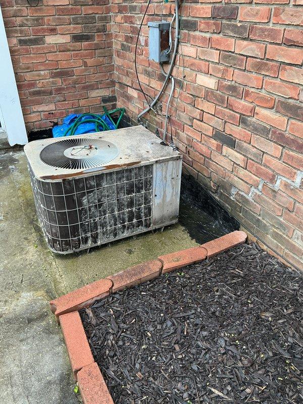 Conducted comprehensive assessment of existing outdoor air conditioning unit and electrical infrastructure for equipment replacement estimate. Documented current system condition including weathered condensing unit on concrete pad with aged electrical disconnect, evaluated utility meter location and conduit routing on exterior brick wall, and photographed site conditions including landscape proximity and foundation clearances to provide accurate replacement specifications.