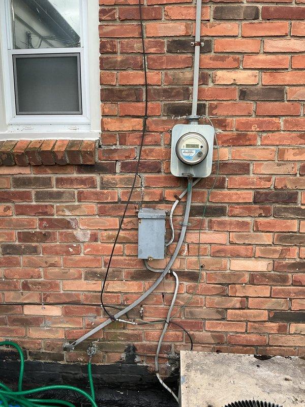 Conducted comprehensive assessment of existing outdoor air conditioning unit and electrical infrastructure for equipment replacement estimate. Documented current system condition including weathered condensing unit on concrete pad with aged electrical disconnect, evaluated utility meter location and conduit routing on exterior brick wall, and photographed site conditions including landscape proximity and foundation clearances to provide accurate replacement specifications.