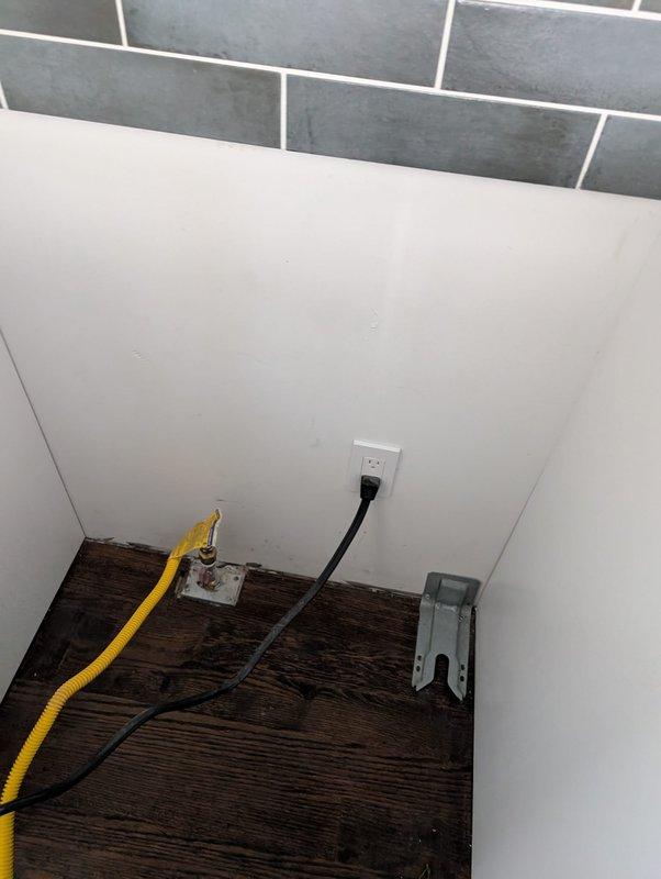 Completed electrical service work at residential property involving circuit breaker panel inspection and outlet installation. Accessed main electrical panel mounted in utility area adjacent to water heater, verified proper breaker configuration and panel labeling. Installed new electrical outlet in corner area near floor level with dark wood flooring and tiled wall section, ensuring proper grounding and secure mounting to meet current electrical code requirements. Connected power supply, tested outlet functionality, and confirmed safe operation of all installed components.