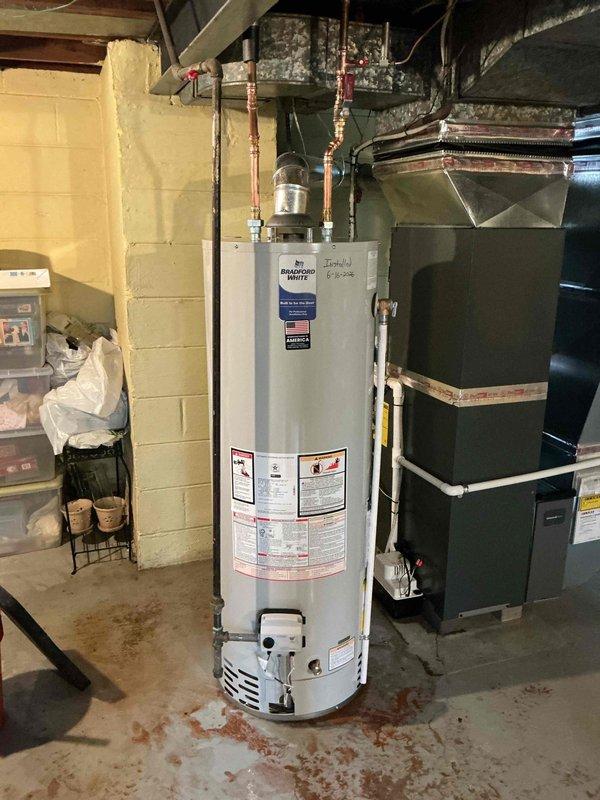 Completed installation of 40-gallon tanked water heater in basement mechanical room. Unit was properly positioned on concrete floor, connected to existing copper supply lines with shut-off valves, and all manufacturer safety labels verified in place. Water heater is operational and installed adjacent to existing HVAC equipment with adequate clearance for service access.