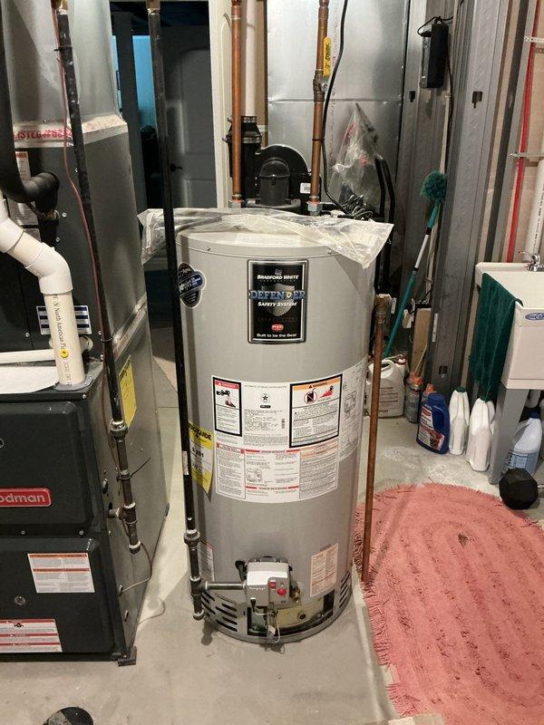 Responded to no hot water complaint at residential property. Upon arrival, inspected tanked water heater unit located in basement utility room alongside HVAC equipment. Evaluated water heater condition, verified all supply and discharge connections including copper piping and color-coded water lines, and assessed circulator pump assembly mounted on top of unit. Confirmed proper electrical connections and examined all safety labels and manufacturer specifications. Restored hot water service to the residence and verified system operation before departure.
