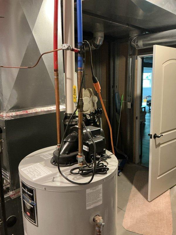 Responded to no hot water complaint at residential property. Upon arrival, inspected tanked water heater unit located in basement utility room alongside HVAC equipment. Evaluated water heater condition, verified all supply and discharge connections including copper piping and color-coded water lines, and assessed circulator pump assembly mounted on top of unit. Confirmed proper electrical connections and examined all safety labels and manufacturer specifications. Restored hot water service to the residence and verified system operation before departure.