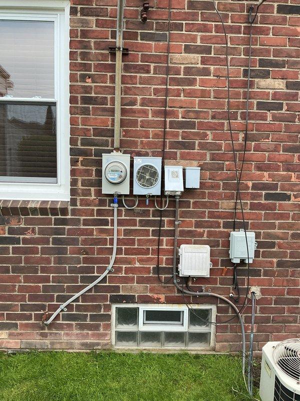 Responded to no cooling complaint affecting entire residence. Upon arrival, found aging cylindrical R-22 air conditioning condenser unit located at rear of property with unknown service history. System evaluation confirmed unit was operating with low refrigerant charge and utilizing obsolete R-22 refrigerant. Due to age of equipment, phase-out of R-22 refrigerant, and overall condition of condenser, provided comprehensive replacement estimate for new cooling system. Documented existing installation including outdoor unit placement, electrical service routing with conduit and disconnect boxes mounted to brick exterior, and current system configuration for replacement planning purposes.