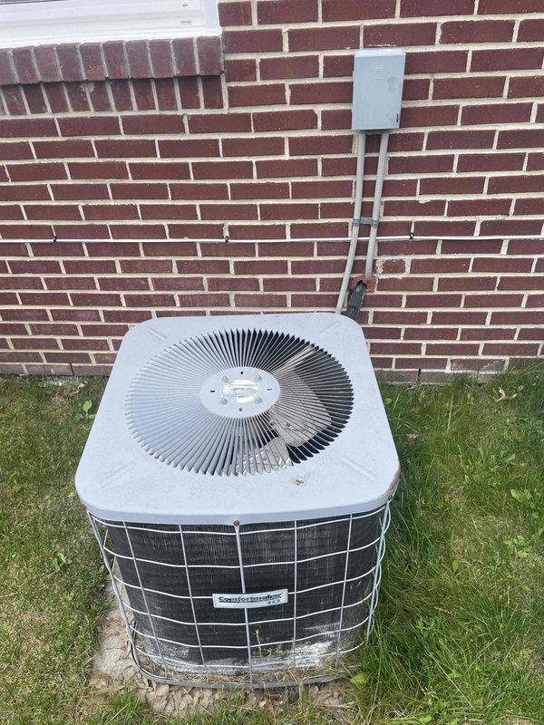 Provided comprehensive estimate for complete air conditioning system replacement at residential property with non-functional outdoor condensing unit over 10 years old located exterior to basement installation with natural gas furnace. Assessed existing equipment condition including weathered condenser unit with fan assembly, electrical disconnect box, refrigerant line sets, and condensate drainage system mounted against brick exterior wall. Prepared replacement specifications for new cooling system compatible with existing natural gas heating infrastructure.