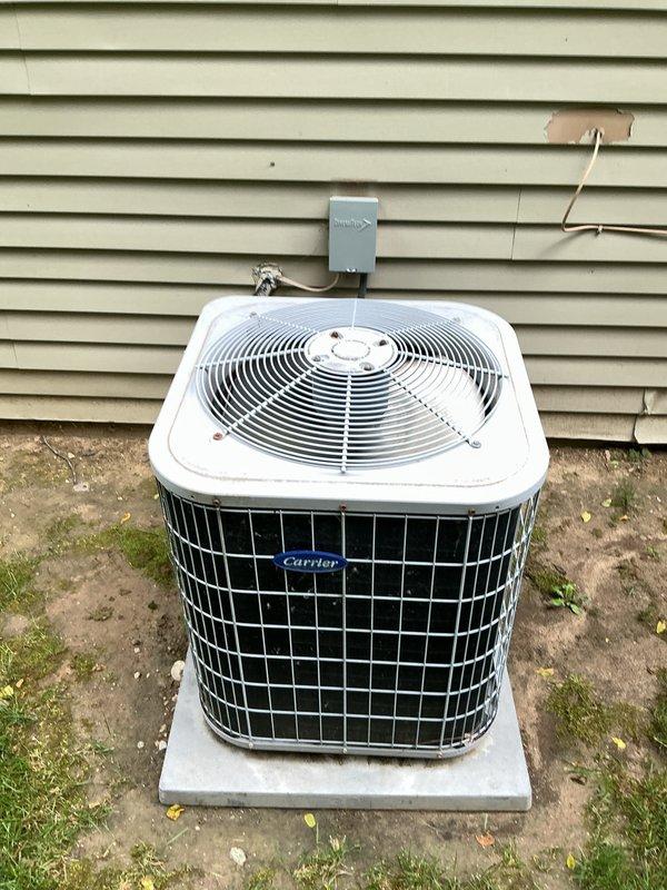 # HVAC Maintenance - Gold AC Inspection

Performed comprehensive Gold AC Inspection on Carrier outdoor condensing unit of unknown age. Conducted complete system evaluation including visual inspection of condenser cabinet, coils, and electrical components. Verified proper operation of compressor and condenser fan motor. Inspected electrical disconnect box and associated wiring for safety compliance. Checked refrigerant line insulation integrity and conduit connections at exterior wall penetration. Evaluated condenser pad levelness and unit stability on concrete base.

Measured temperature differential across evaporator coil and verified proper airflow through system. Inspected indoor evaporator coil and associated copper refrigerant lines in basement mechanical area. Noted presence of condensation or frost formation on U-bend piping configuration near water heater, indicating potential low refrigerant charge or airflow restriction. Examined brass fittings, joints, and pressure relief co