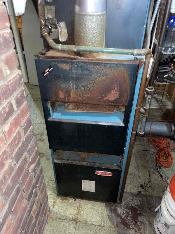 Provided estimate for replacement of non-operational air conditioning system and aging natural gas furnace located in basement. Existing furnace exhibits extensive rust and corrosion on exterior panels and blower compartment, indicating advanced deterioration and end of serviceable life. Current thermostat displaying abnormal reading requires replacement with new equipment installation.