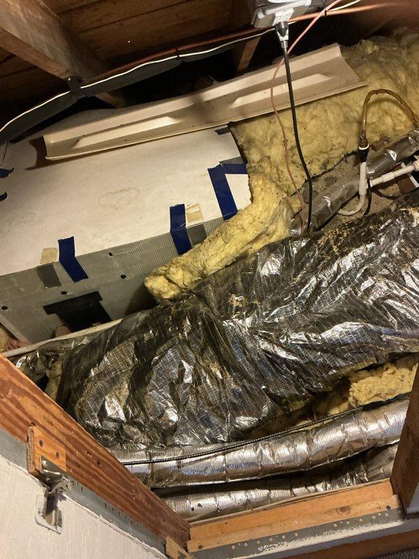 Responded to no cooling complaint on 14-year-old Unico system with outdoor condenser and attic-mounted air handler. Accessed attic equipment, inspected air handler unit, flexible ductwork, refrigerant lines, and electrical connections for proper operation and potential failure points. Documented system condition with photos showing air handler, insulated ductwork installation, and mechanical components in attic space.