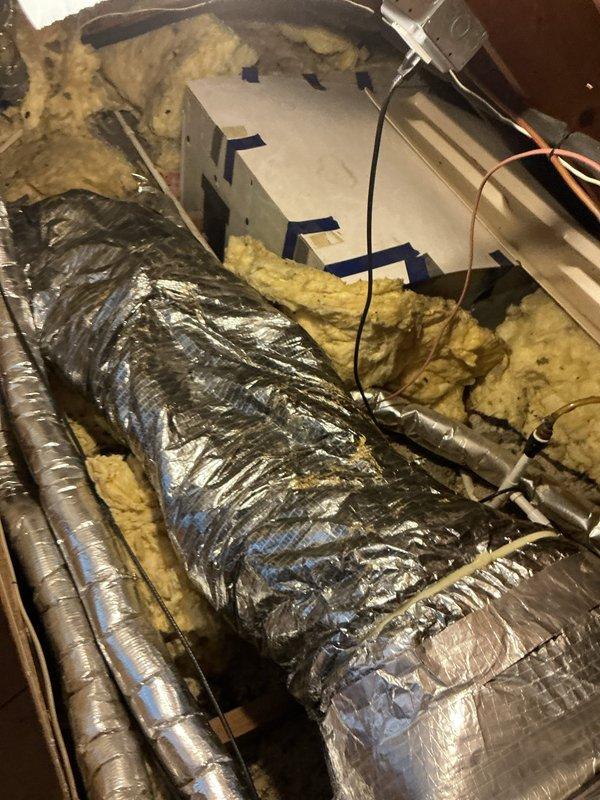 Responded to no cooling complaint on 14-year-old Unico system with outdoor condenser and attic-mounted air handler. Accessed attic equipment, inspected air handler unit, flexible ductwork, refrigerant lines, and electrical connections for proper operation and potential failure points. Documented system condition with photos showing air handler, insulated ductwork installation, and mechanical components in attic space.