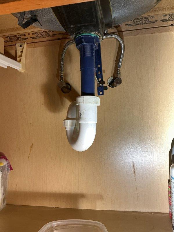 Responded to emergency service call for leaking faucet at 25-year-old residential property. Successfully installed two new faucet fixtures—one chrome bathroom vanity faucet at double-sink vanity with speckled gray countertop, and one kitchen faucet connected to existing garbage disposal and dishwasher tailpiece assembly with PVC P-trap configuration. All connections tested and verified leak-free with proper water pressure and drainage function.