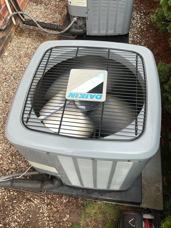 Completed comprehensive Gold AC inspection on a dual-zone residential system featuring two Daikin condensing units, approximately 4 years old, with indoor air handlers located in the basement. Performed thorough multi-point inspection of both outdoor condensing units including visual assessment of cabinet condition, refrigerant line connections, electrical conduit, mounting pads, and overall equipment operation. Both units found to be in proper working condition with adequate airflow through louvers, secure refrigerant line connections, and proper installation on gravel pad with vibration-dampening pads.
