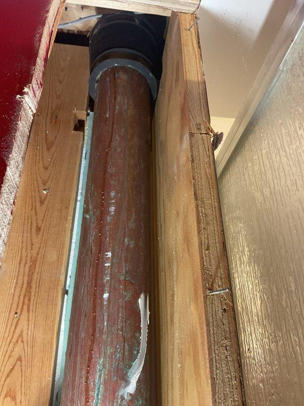 Responded to a basement water leak in a 60-year-old residential property where moisture intrusion had been occurring for several weeks. Upon inspection, discovered severely corroded cast iron drain pipe within the wall cavity, exhibiting extensive rust deterioration and mineral deposits indicative of long-term water seepage. 

Removed section of wall material to access the compromised plumbing infrastructure. Found the vertical drain stack and toilet flange assembly had deteriorated significantly due to age and continuous water exposure. The corroded pipe sections showed brown rust patina with white efflorescence, confirming active leak conditions. A rubber coupling connection near the upper portion of the pipe was also inspected for integrity.

Performed necessary repairs to address the water leak source, including pipe section replacement or reinforcement where corrosion had compromised structural integrity. Ensured proper sealing of all plumbing connections to prevent future moistur