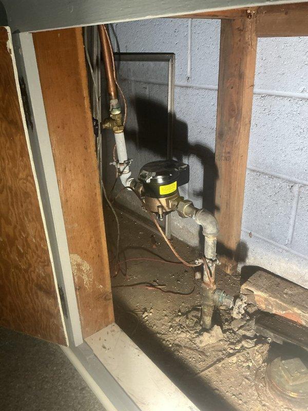 Responded to intermittent drainage backup in basement laundry room near washing machine. Accessed plumbing system through cabinet opening and inspected sump pump assembly with copper piping connections. Cleared obstruction from drain line, verified pump operation, and tested system to confirm proper water flow and drainage restored to normal function.