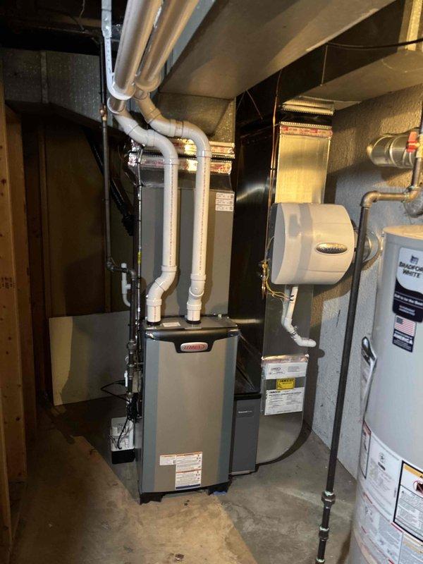 Completed full HVAC system installation in residential basement including 70,000 BTU Lennox furnace, 3-ton air conditioning system, whole-home humidifier, and 50-gallon water heater. All equipment positioned on left side of utility room with proper clearances for service access. Installed white PVC venting for high-efficiency furnace routed through ceiling joists, connected humidifier to HVAC system with appropriate supply lines, and integrated all electrical connections per code requirements. Reconnected existing ductwork to new furnace unit and verified proper airflow throughout system. Commissioned AC system using digital manifold gauges, confirmed refrigerant pressures (108.0 psi low side, 207.4 psi high side), verified superheat at 100.0°F and subcooling parameters within manufacturer specifications. Water heater installed with code-compliant venting and plumbing connections. Mechanical permit secured and all work performed to local building code standards. System tested and opera