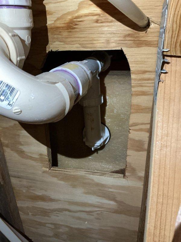 Responded to service call for bathroom plumbing repairs involving faucet and drainage issues. Replaced drain plug assembly and addressed loose water spout on bathroom sink by disassembling faucet components, removing valve stem cartridge, and securing mounting hardware with new gaskets and seals. Completed replacement of tub fixtures as requested. During inspection, identified water leakage beneath flooring through access cutout, revealing compromised PVC drain trap connection with visible water accumulation on subfloor. Documented plumbing conditions with photographic evidence showing exposed valve assemblies, chrome fixtures, and underneath drainage system requiring attention to prevent further water damage.
