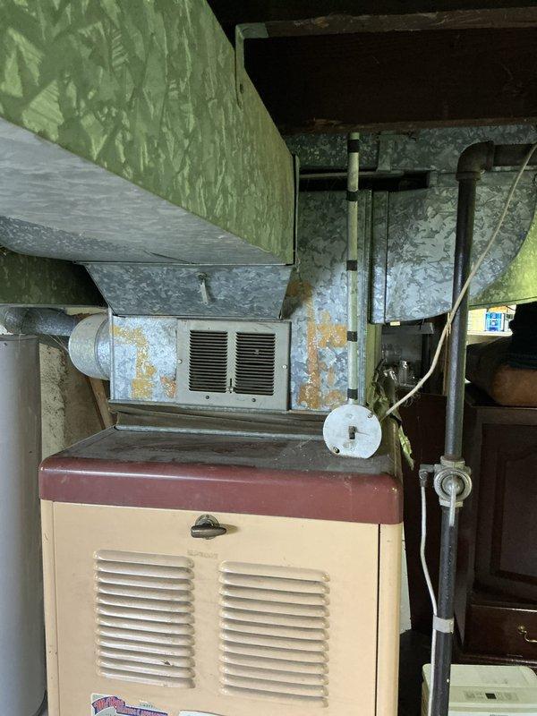 Conducted comprehensive site assessment for full HVAC system replacement in residential property. Evaluated existing aging furnace unit and ductwork infrastructure currently installed in basement mechanical room. Documented current system configuration including beige cabinet-style furnace with visible wear, discoloration, and outdated components. Assessed galvanized metal ductwork showing significant rust staining, corrosion, and age-related deterioration throughout distribution system. Photographed equipment layout, plenum connections, and surrounding mechanical space to develop accurate replacement specifications. Evaluated structural constraints, clearances, and accessibility for new furnace installation and addition of central air conditioning system. Identified necessary modifications to existing duct system to accommodate AC integration. Provided detailed estimate for complete system replacement including new high-efficiency furnace, central air conditioning unit, and any requir
