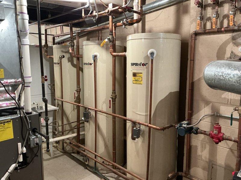 Service technician responded to customer concerns regarding inconsistent water temperature in multiple showers producing lukewarm water. Upon inspection of the mechanical room, evaluated the hot water distribution system including multiple water heaters and extensive copper piping network with circulation components. Documented the existing plumbing infrastructure and identified potential cartridge failures in shower valve assemblies as the likely cause of temperature issues. Recommended scheduling a licensed plumber to provide estimate for circulation pump evaluation and replacement of defective shower cartridges to restore proper hot water delivery throughout the residence.