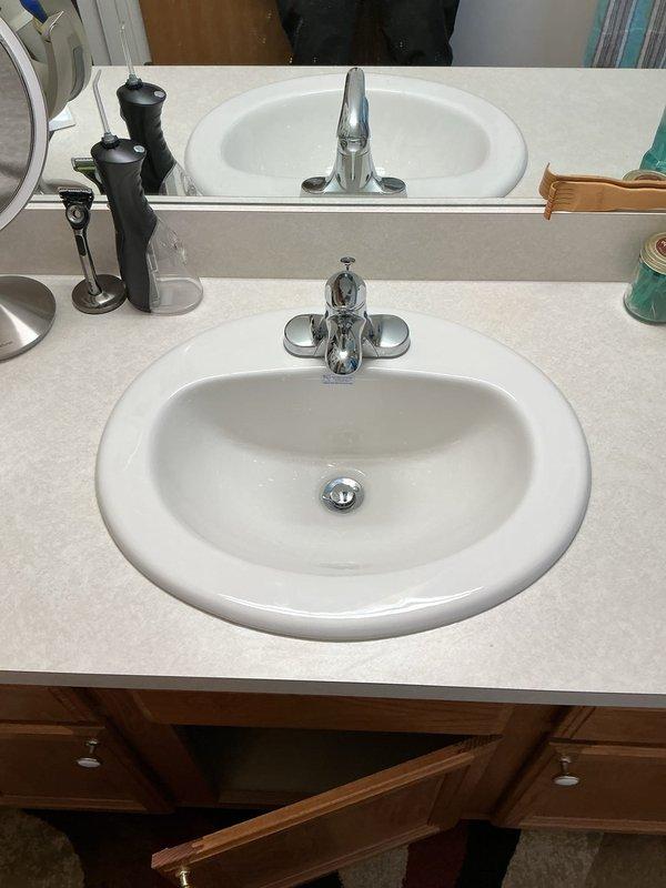 Completed plumbing repair service at residential bathroom vanity with dual sink configuration. Addressed plumbing infrastructure beneath vanity cabinet, working with existing PVC drain lines and supply connections serving chrome dual-handle faucets on both oval sinks. Performed necessary repairs to restore proper functionality to the vanity plumbing system.