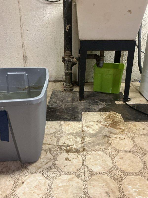 Responded to service call for toilet flushing issue causing water backup into washing machine sink. Upon arrival, inspected bathroom toilet and drainage system, then examined utility area plumbing connections near water heater. Diagnosed main drain line blockage affecting multiple fixtures due to shared drainage pathway between toilet and laundry sink. Cleared obstruction from drain line to restore proper flow and prevent cross-contamination between fixtures. Verified successful flush operation and confirmed washing machine sink no longer experiencing backup issues.