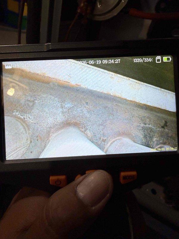 Responded to service call for 10+ year old air conditioning system making unusual noise during operation. Performed diagnostic inspection of outdoor condensing unit in backyard and indoor evaporator coil connected to basement furnace system. Utilized inspection camera to examine internal components, revealing significant rust and corrosion on metal surfaces within the system. Conducted temperature measurements on refrigerant lines and evaporator coil assembly, recording suction line temperature at 53.3°F. Documented condition of equipment showing signs of age-related deterioration and corrosion that may be contributing to operational noise. Provided findings and recommendations for addressing corroded components to restore quiet operation.