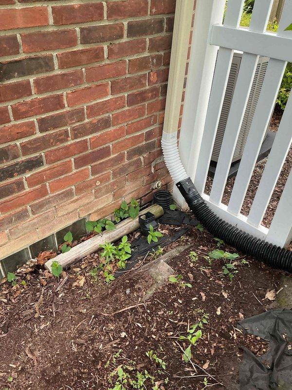 Conducted on-site evaluation of existing sump pump system located in basement area. Assessed current sump pump basin installation with elevated water level and operational green submersible pump unit secured with PVC discharge piping. Inspected exterior discharge line routing, including black corrugated drainage pipe extending from foundation along white-sided structure into landscaped area with appropriate drainage away from building. Provided comprehensive estimate for sump pump system replacement or repair based on observed conditions and homeowner requirements.