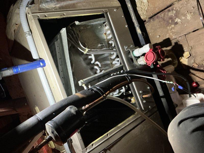 Responded to report of water leak from attic-mounted furnace occurring during laundry operation, with visible condensation damage on interior ceiling. Inspected 10-year-old HVAC system and evaporator coil assembly, identifying condensate drainage issue affecting air handler unit. Confirmed water staining on ceiling corner consistent with condensate overflow from furnace location above. Accessed internal components through air handler panel, examined evaporator coils, refrigerant lines, and condensate management system to diagnose source of moisture intrusion and recommend corrective action.