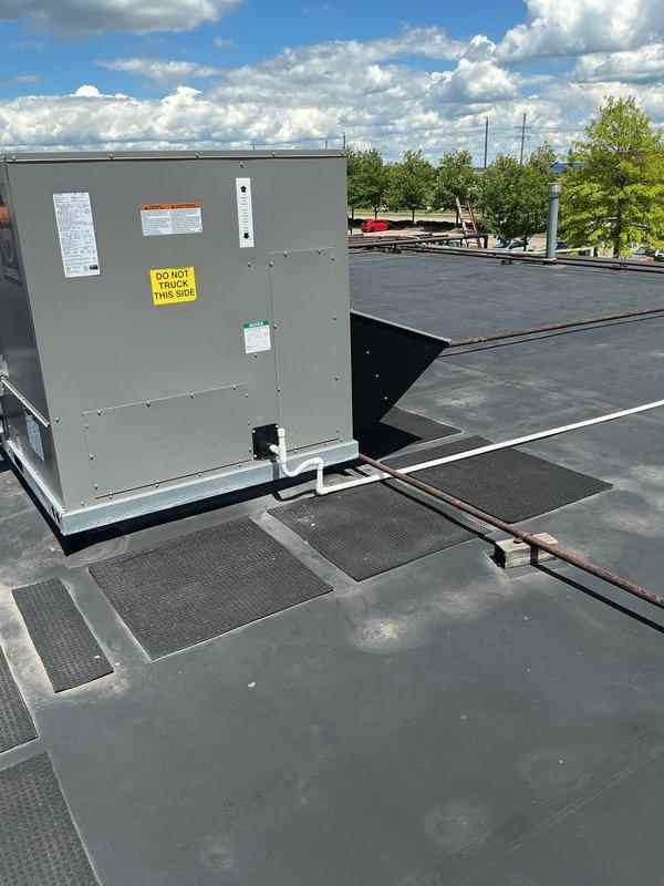Completed installation of Rheem commercial rooftop unit (RTU) on flat membrane roof system. Unit was properly positioned and secured with appropriate walkway pads installed for maintenance access, all electrical connections completed, and weatherproofing verified per manufacturer specifications. Equipment tested and confirmed operational with no visible defects or installation issues.