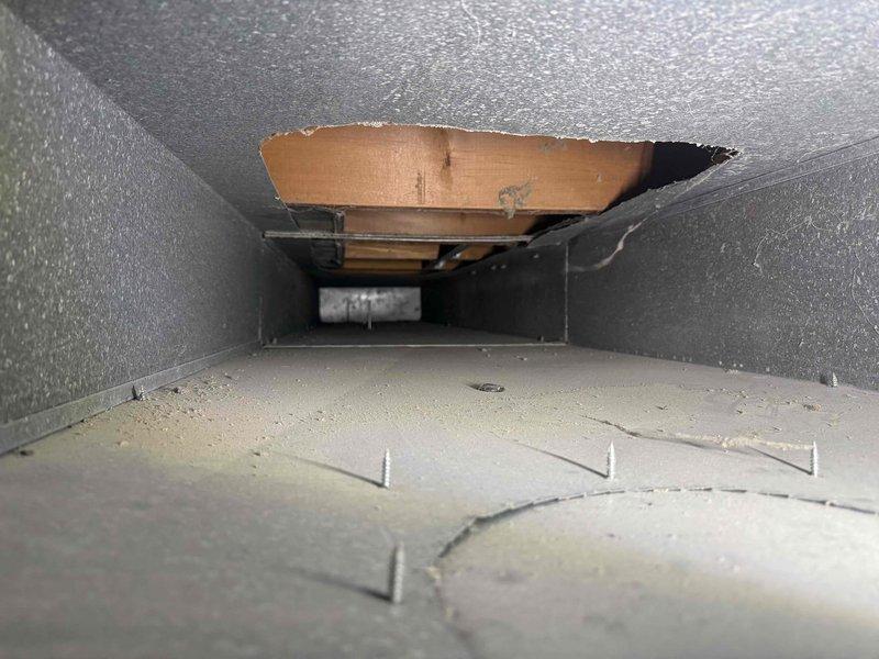 Responded to callback for 1-month-old AC unit in basement experiencing persistent issues following a power outage. Upon inspection, discovered significant damage to supply ductwork with torn metal sections exposing cardboard backing material and compromised duct integrity. Documented extensive deterioration of ductwork interior, including separated seams, damaged insulation backing, and debris accumulation on heat exchange surfaces that could restrict airflow and reduce system efficiency.