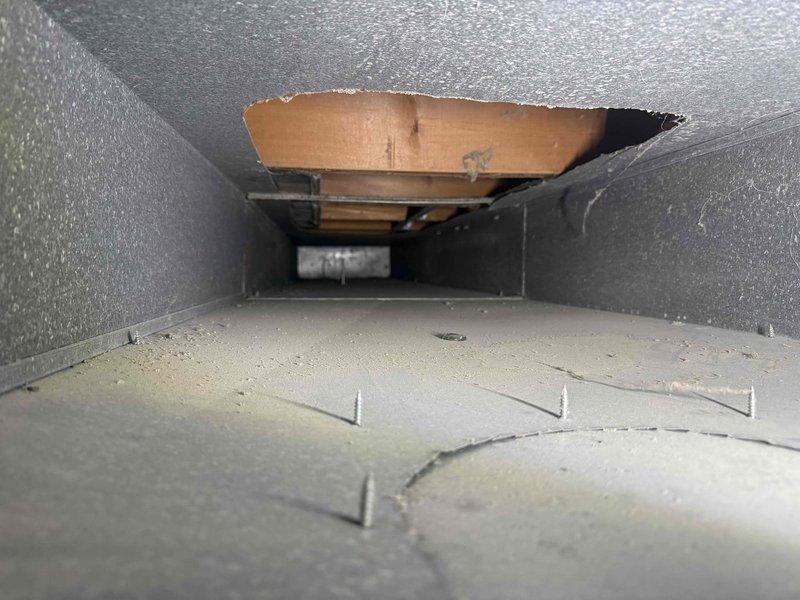Responded to callback for 1-month-old AC unit in basement experiencing persistent issues following a power outage. Upon inspection, discovered significant damage to supply ductwork with torn metal sections exposing cardboard backing material and compromised duct integrity. Documented extensive deterioration of ductwork interior, including separated seams, damaged insulation backing, and debris accumulation on heat exchange surfaces that could restrict airflow and reduce system efficiency.