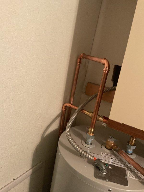 Completed installation of residential water heater in basement utility area. Connected hot and cold water supply lines using copper piping with proper dielectric unions and brass fittings to prevent galvanic corrosion. Installed flexible gas supply line with corrugated metallic connector to fuel source. All plumbing connections secured and tested for proper operation and leak-free performance.