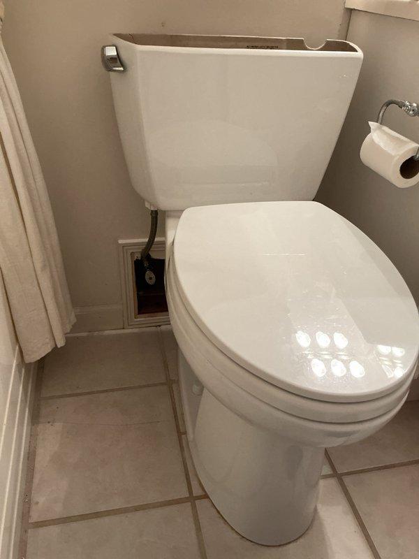 Inspected residential toilet system and documented existing conditions. Tank interior revealed significant mineral deposits, hard water staining, and a visible crack in the upper left portion of the ceramic tank wall. Fill valve assembly with float mechanism and flush valve with rubber flapper were operational but showing age-related wear consistent with the deteriorated tank condition. Photographed both exterior toilet installation and internal tank components for service documentation and recommended replacement due to structural compromise of the tank.