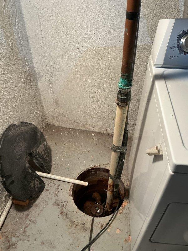 Completed new sump pump installation in basement of 55-year-old residence with no prior system in place. Excavated and installed sump basin in concrete floor, mounted submersible pump with discharge piping routed vertically through copper pipe assembly, and connected electrical supply with wall-mounted control switch for automatic operation to prevent basement flooding.