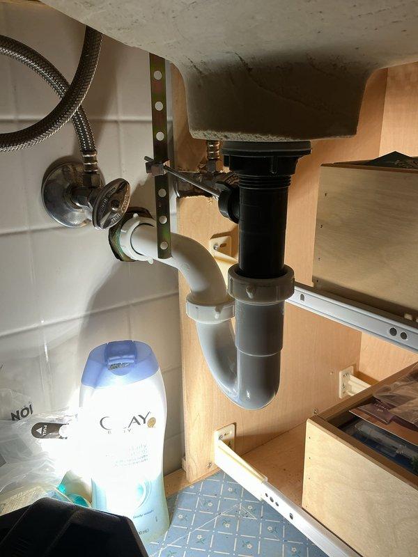 Responded to service call for leaking kitchen faucet. Upon inspection, examined supply lines, shut-off valves, and drain assemblies under both kitchen and bathroom sinks to identify source of leak. Inspected braided metal supply lines, chrome shut-off valves, P-trap assemblies, and all connection points for signs of water damage or active leaking. Documented existing plumbing configuration including PVC drain piping, compression fittings, and flexible supply lines. Verified proper operation of shut-off valves and assessed condition of all visible plumbing components to resolve reported leak issue.