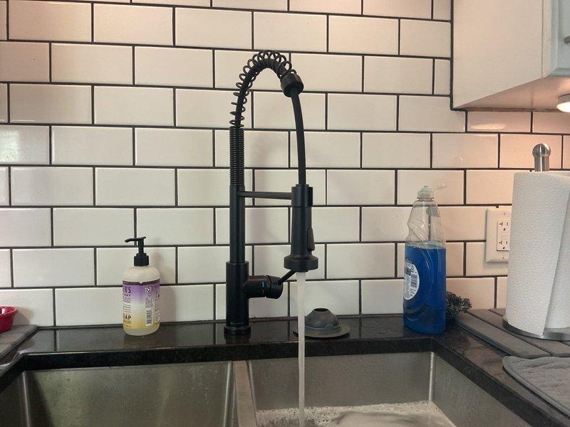Completed installation of garbage disposal unit under double-basin kitchen sink with proper electrical connection and drain configuration. Installed white PVC P-trap assembly with secure threaded connections to accommodate disposal discharge and secondary sink drain. Verified proper operation of disposal unit, tested all drain connections for leaks, and ensured proper venting of the drainage system.