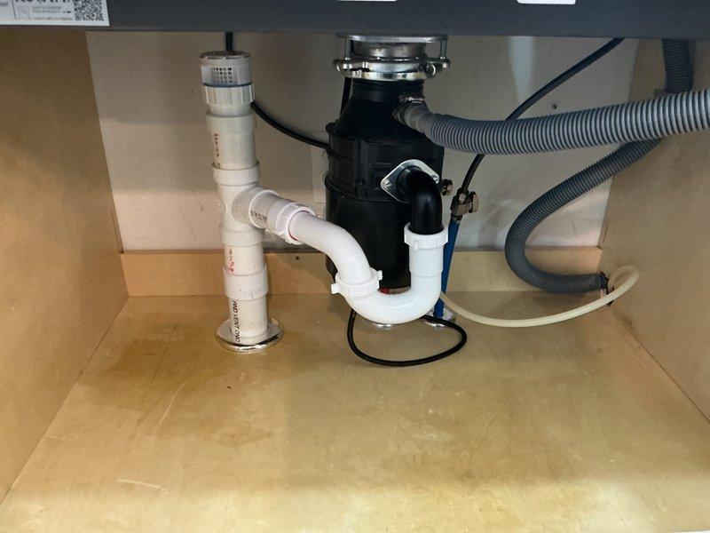 Completed continuation service on multiple plumbing fixtures throughout the residence, including four bathroom faucets, kitchen faucet, kitchen water spigot, and garbage disposal. Inspected and serviced kitchen sink installation featuring single-handle pull-down faucet with brushed stainless steel finish and verified proper operation of black garbage disposal unit with associated PVC P-trap drainage system and electrical connections. All fixtures tested and confirmed to be functioning properly upon completion.