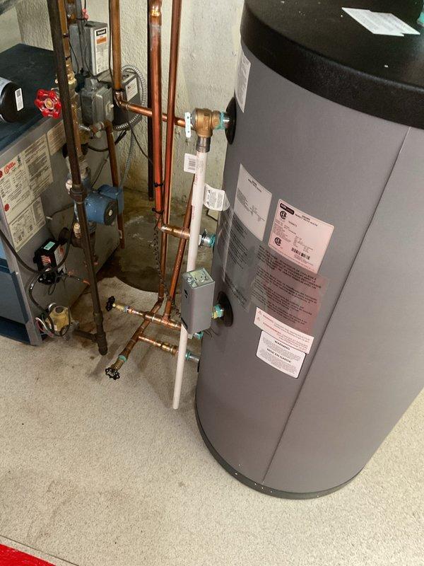 Completed installation of indirect water heater system in residential basement utility room. Installed large-capacity cylindrical storage tank with integrated pump unit, configured all copper supply and return piping with appropriate shut-off valves, pressure relief mechanisms, and connection fittings to existing boiler system. Applied for and coordinated mechanical permit for hot water heater reconnection, processed payment, and documented completed installation with photographs showing proper plumbing configuration and professional-grade workmanship.