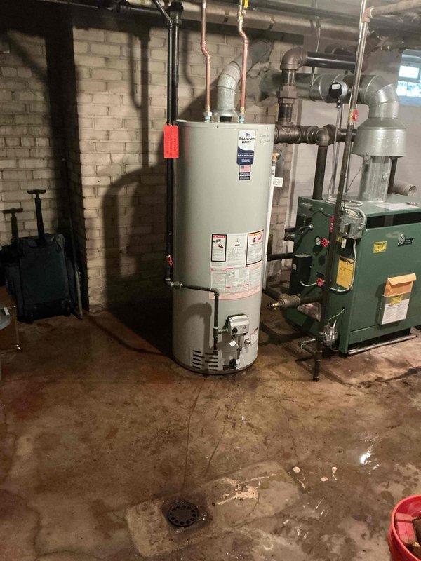 # Plumbing Install - Tanked Water Heater

Successfully installed a 50-gallon residential tanked water heater in the basement mechanical room. The installation included connecting copper supply lines, establishing proper venting, installing a temperature and pressure relief valve with discharge piping, and reconnecting all water supply connections to restore hot water service to the residence. All connections were pressure tested and verified for proper operation alongside the existing green boiler heating system.