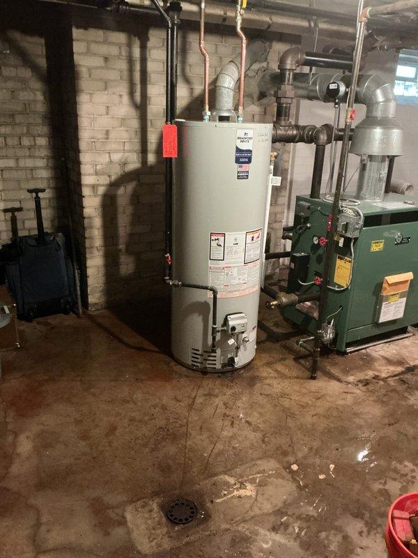 # Plumbing Install - Tanked Water Heater

Successfully installed a 50-gallon residential tanked water heater in the basement mechanical room. The installation included connecting copper supply lines, establishing proper venting, installing a temperature and pressure relief valve with discharge piping, and reconnecting all water supply connections to restore hot water service to the residence. All connections were pressure tested and verified for proper operation alongside the existing green boiler heating system.