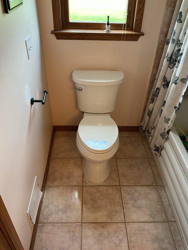 Completed toilet installation in residential bathroom, securing unit to flange and connecting water supply line. Verified proper flush operation, checked for leaks at all connection points, and confirmed stable mounting to ensure optimal performance.