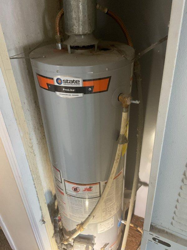 Responded to service call for leaking State Industries ProLine tanked water heater in mobile home installation, originally installed in 2018. Upon inspection, confirmed active leak at tank base with visible water damage and corrosion on copper piping connections. Noted absence of dedicated shut-off valve for water heater, requiring main water supply to home to be shut off for any service work. Documented warranty discrepancy between customer records indicating 10-year tank/5-year labor coverage and company records showing 6-year tank warranty. Photographed unit condition, piping connections, temperature and pressure relief valve assembly, and evidence of mineral deposits and copper oxidation on fittings. Tank installed in confined utility closet space with standard residential venting and plumbing connections. Recommended immediate attention due to active leak and lack of isolation valve for future service accessibility.