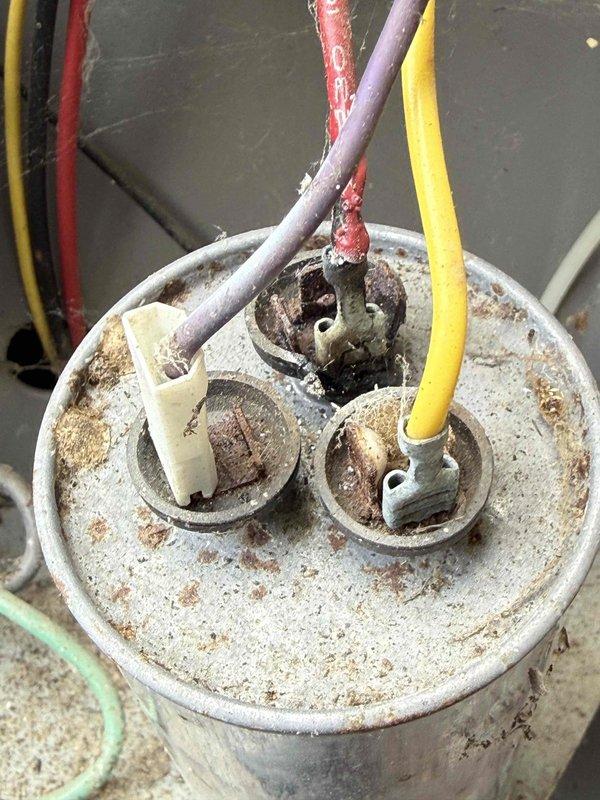 Completed comprehensive Gold AC inspection on 20-year-old basement-located air handler system. Performed full system evaluation including electrical component assessment, documenting significant corrosion and weathering on capacitor housing with rust spots and discoloration throughout metal surfaces. Identified deteriorated wire insulation on red conductor at capacitor terminal connections, along with visible corrosion on terminal fittings and junction box components. Noted extensive rust and degradation on outdoor electrical junction housing with weathered wire insulation on multiple conductors. Photographically documented all findings including compromised electrical connections, aged tape insulation material, and overall component deterioration consistent with extended environmental exposure. System currently operational but exhibits advanced age-related wear requiring attention to electrical connections and capacitor condition for continued safe operation.