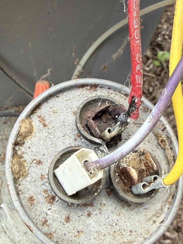 Completed comprehensive Gold AC inspection on 20-year-old basement-located air handler system. Performed full system evaluation including electrical component assessment, documenting significant corrosion and weathering on capacitor housing with rust spots and discoloration throughout metal surfaces. Identified deteriorated wire insulation on red conductor at capacitor terminal connections, along with visible corrosion on terminal fittings and junction box components. Noted extensive rust and degradation on outdoor electrical junction housing with weathered wire insulation on multiple conductors. Photographically documented all findings including compromised electrical connections, aged tape insulation material, and overall component deterioration consistent with extended environmental exposure. System currently operational but exhibits advanced age-related wear requiring attention to electrical connections and capacitor condition for continued safe operation.