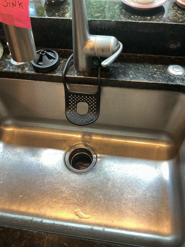 Responded to complete kitchen sink blockage in 1998-built residence where previous DIY attempts including garbage disposal replacement, P-trap disassembly, 10-15 ft cable snaking, and chemical treatments had failed to resolve the issue. Upon inspection, verified new InSinkErator disposal installation and existing white PVC drain configuration beneath single-bowl stainless steel sink. Performed advanced drain clearing procedures beyond the initial 15 feet of line previously attempted, successfully locating and removing obstruction in main drain line that had caused progressive drainage deterioration over the preceding week. Tested system flow through disposal unit and drain assembly, confirming full restoration of drainage capacity and proper operation of all components.