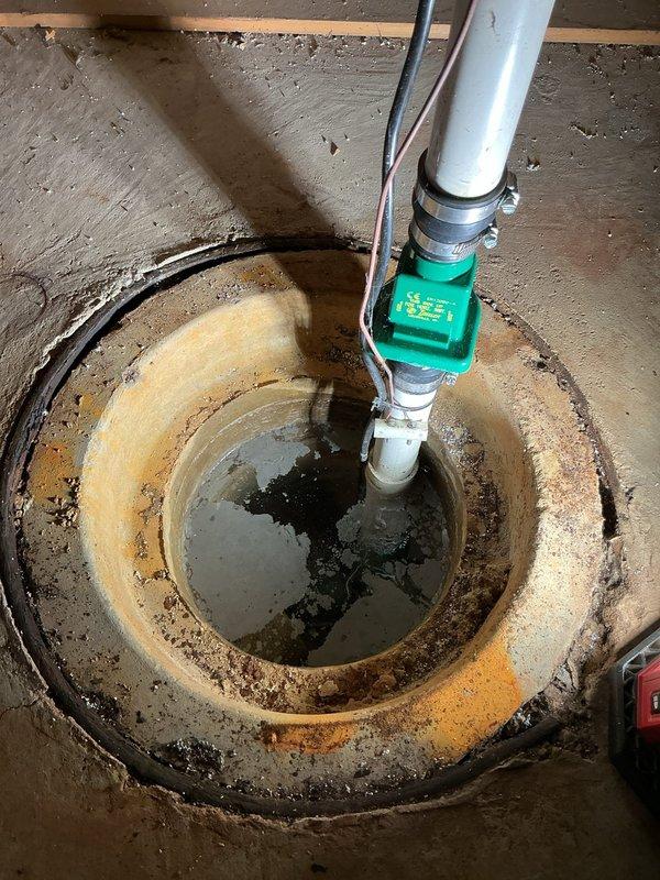 Completed sump pump replacement in basement of 45-year-old residential property. Removed existing submersible pump unit from circular basin showing significant age-related deterioration, mineral deposits, and water staining. Installed new submersible sump pump with float switch mechanism, secured vertical PVC discharge piping with proper couplings and support brackets, and verified electrical connections. System tested and operational; provided warranty information to homeowner as requested.