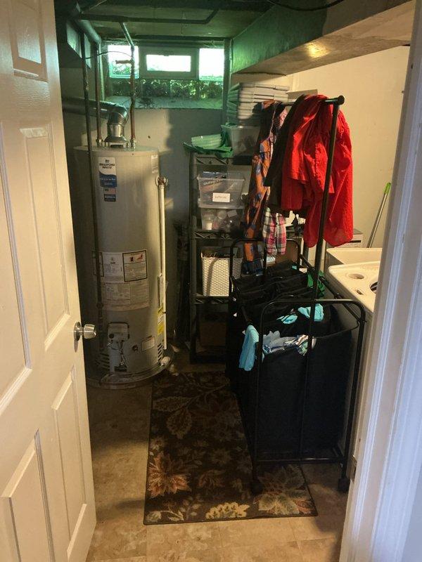 Conducted inspection of water heater installation in utility room and identified code violation regarding inadequate combustion air supply. The water heater room requires proper ventilation with two combustion air openings—one positioned high near the ceiling and one low near the floor—sized at 1 square inch per 1,000 BTU input of installed appliances, with a minimum of 100 square inches per opening. Documented existing conditions with photographs showing the confined utility space housing the water heater and related mechanical equipment, noting the absence of code-compliant combustion air openings necessary for safe appliance operation.