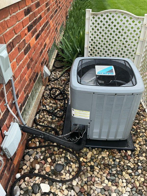 Completed comprehensive Gold AC tune-up and inspection on six-year-old residential air conditioning system located at rear of property. Performed standard maintenance protocol including examination of outdoor condenser unit, refrigerant lines, and indoor air handler components. During attic inspection, discovered significant accumulation of wood debris and sawdust near HVAC ductwork and copper refrigerant lines, likely indicating pest activity or recent construction work in the space. Documented conditions with photographs showing debris on platform near cylindrical metal ductwork and copper pipe connections. Verified outdoor condenser unit operational status, confirmed proper mounting on pad with adequate clearance, inspected refrigerant line routing across landscaped area, and noted all manufacturer labels intact. System currently functioning within normal parameters with no immediate mechanical concerns identified, though recommend addressing attic debris accumulation to prevent pot
